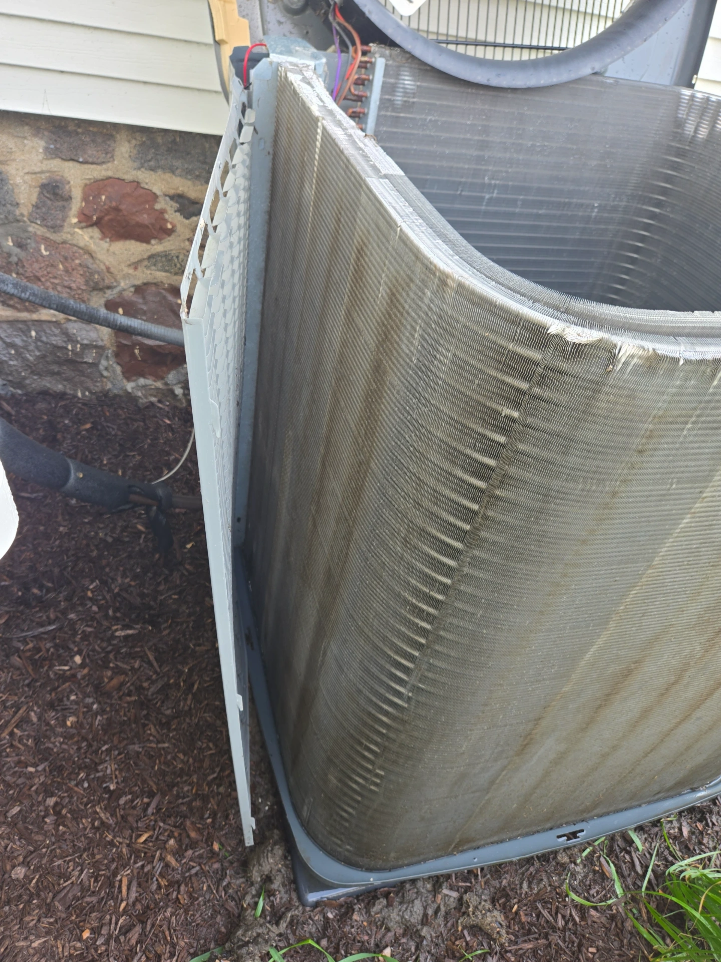 Outdoor AC condenser with dirty coils before a Great Lakes Comfort maintenance visit in Howell, MI