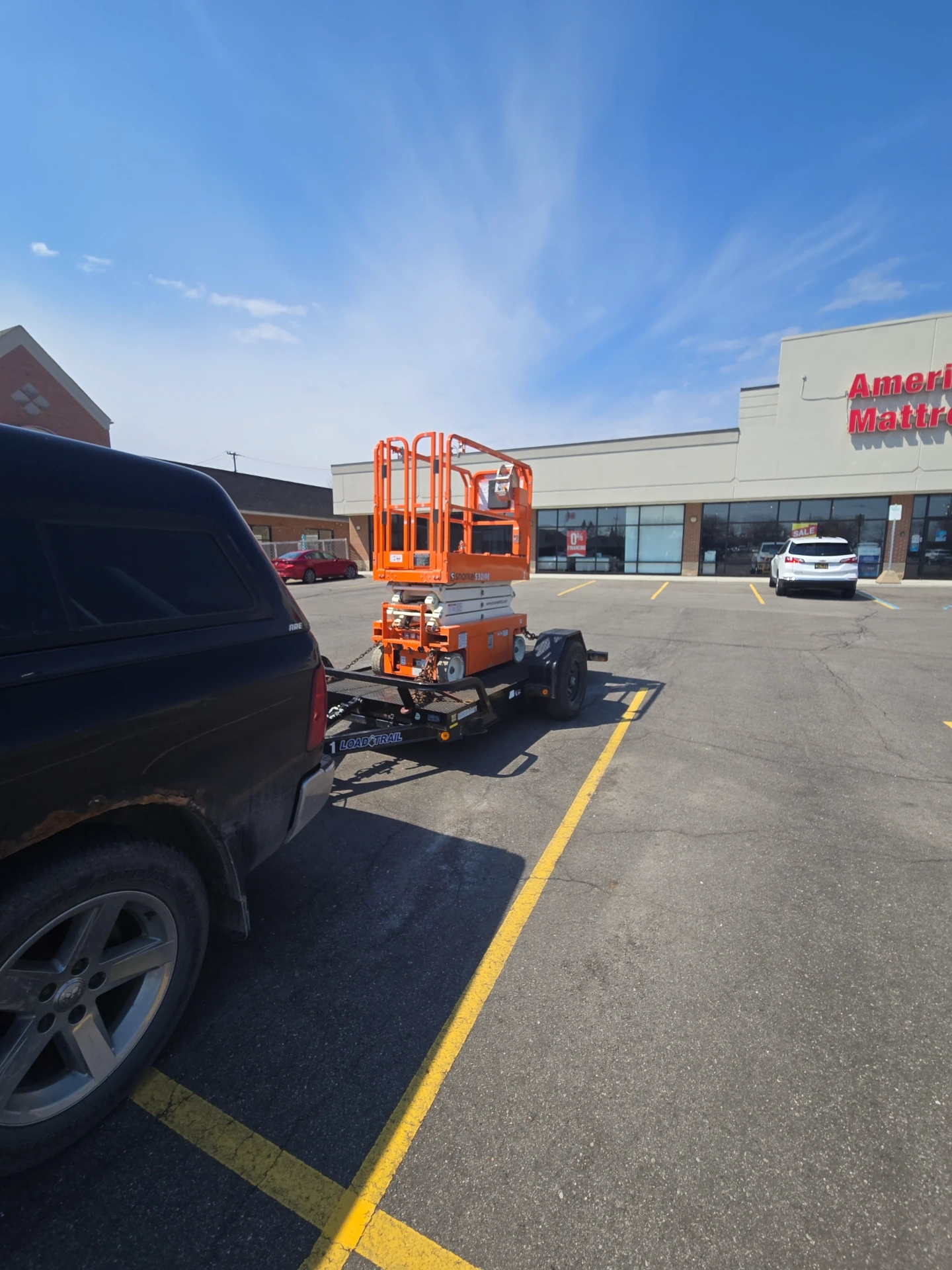 Great Lakes Comfort HVAC install crew loading a scissor lift onto a trailer in Howell, MI